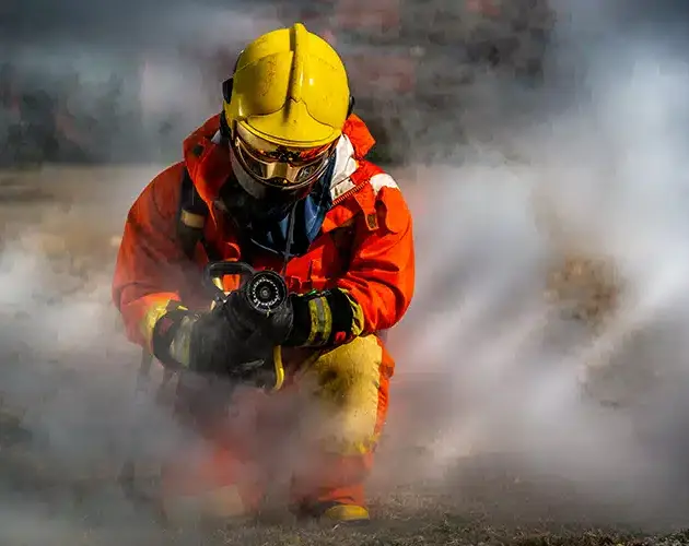 travailleur en combinaison contre le feu et avec un masque respiratoire mis à genou