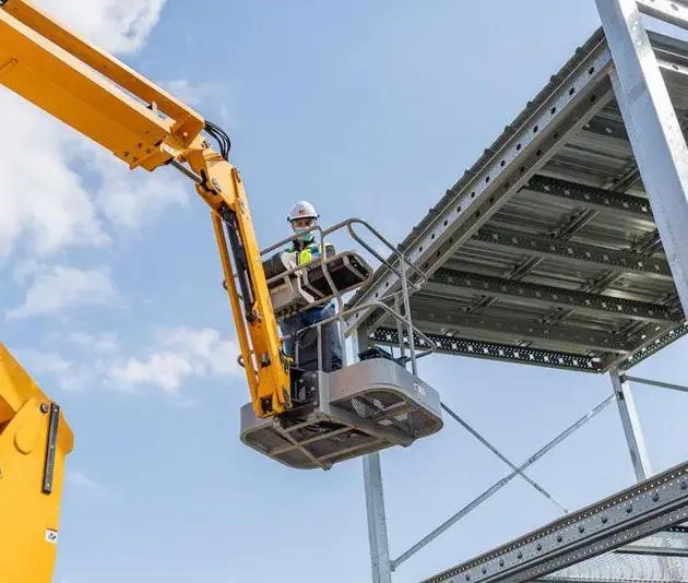 employé de chantier sur une nacelle qui répare une structure