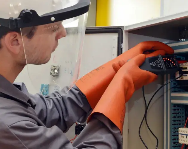 travailleur qui réalise des test sur un compteur électrique muni de matériel et d'équipement de protection