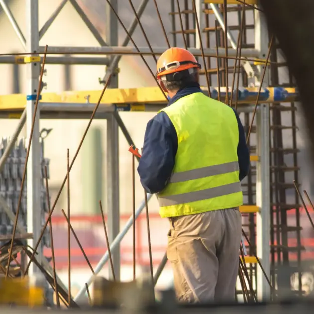 personne sur un chantier muni d'équipement de protection qui est en train de travailler sur un échafaudage
