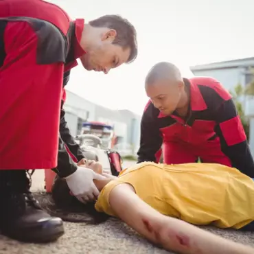 deux personnes entrain d'appliquer les premiers gestes de secourisme sur un personne blessé et à terre