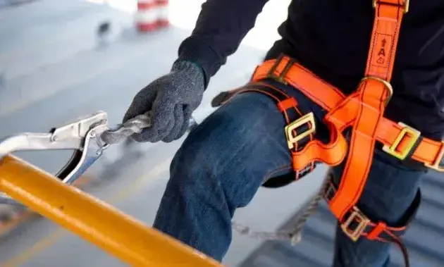 travailleur muni d'un harnais de sécurité et attaché à une infrastructure en train de travailler en hauteur